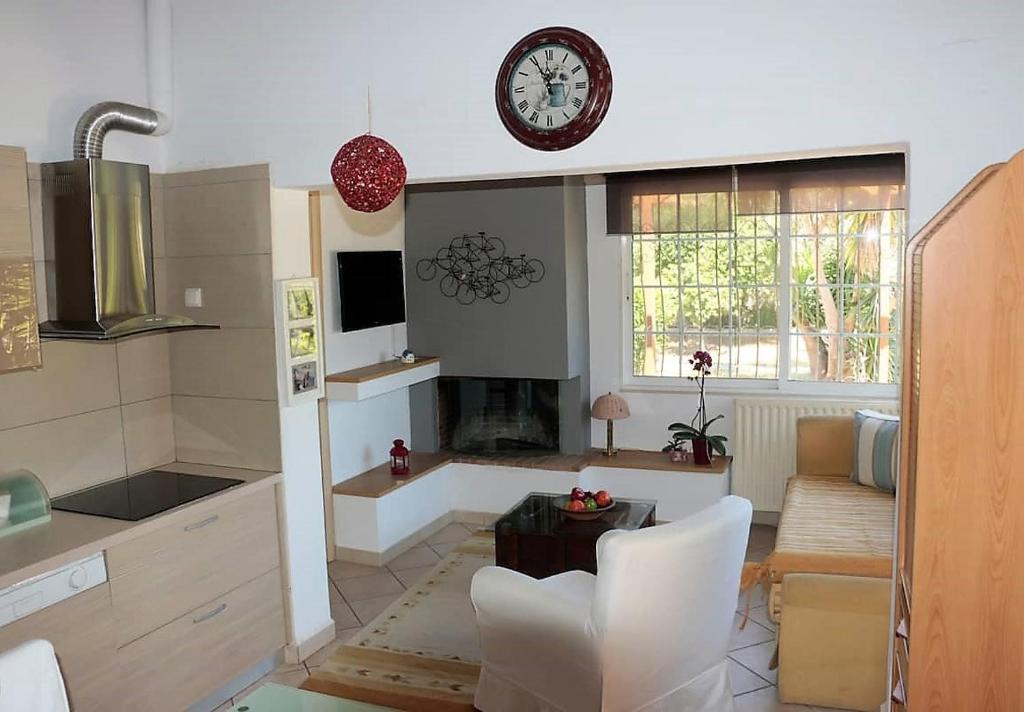 a kitchen with a table and a clock on the wall at Kato Posidonia Sounio. The house with lemon trees in Lavrio