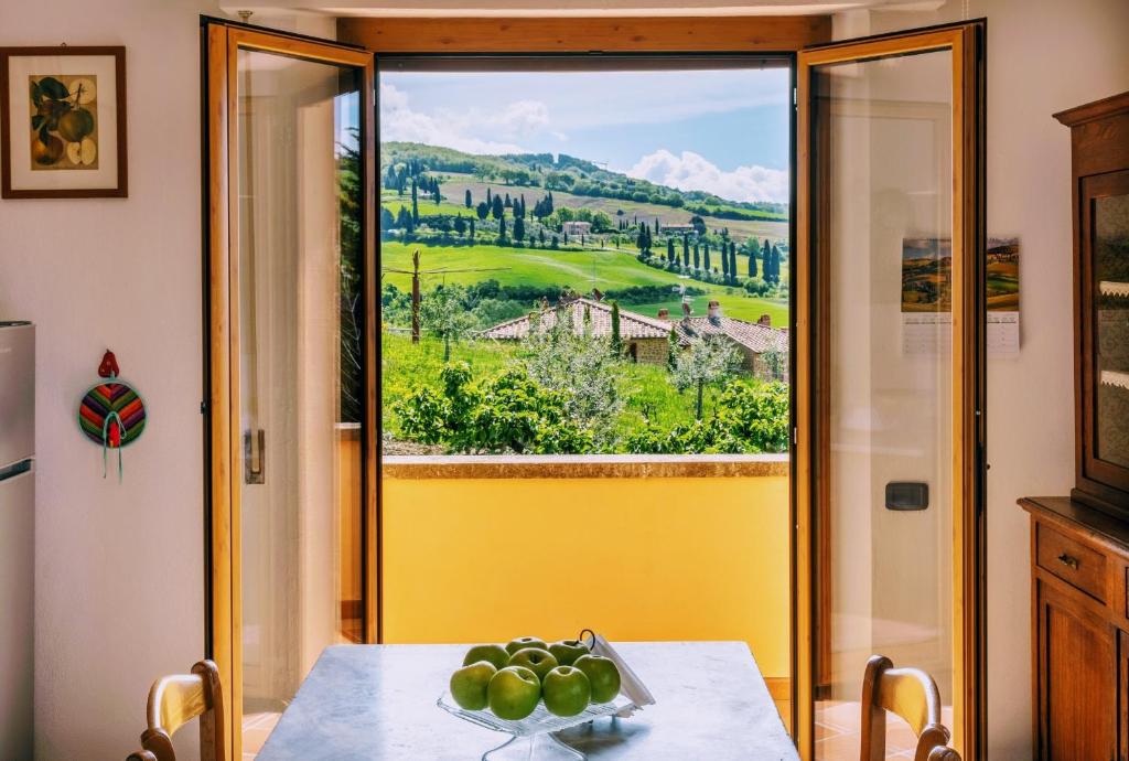 a table with a bowl of fruit on it in front of a window at Villa PoliFlora in Monticchiello