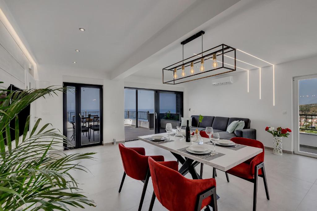 a dining room with a table and red chairs at Villa Pejic NEW, PENTHOUSE in Podgora