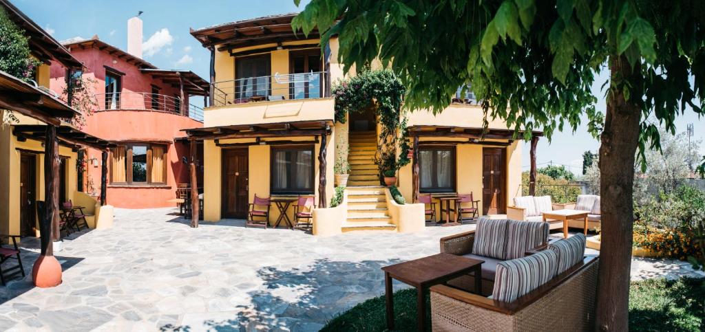 a house with a patio with chairs and a tree at Alkifron Hotel in Kala Nera