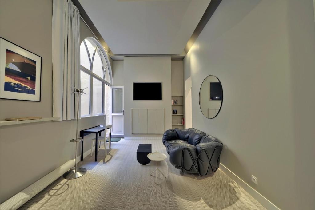 sala de estar con silla azul y ventana en Le Nuage - Studio design à Triangle d'Or, en Burdeos