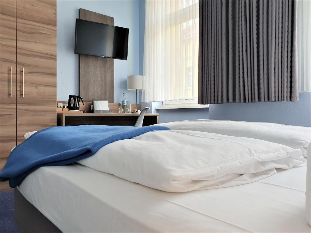 a bedroom with a white bed with a tv on the wall at Melarose Feng Shui Hotel in Berlin