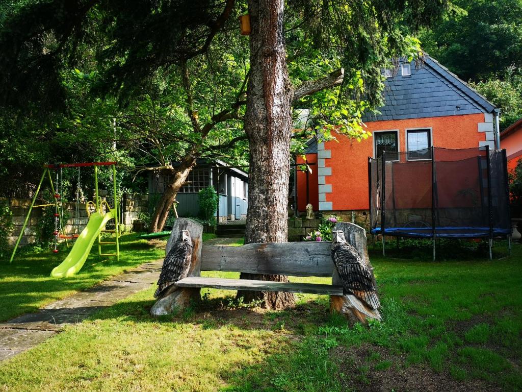 un banco de parque junto a un árbol con parque infantil en Ferienhaus Franz - an der Elbe, mit großem Garten, en Pirna
