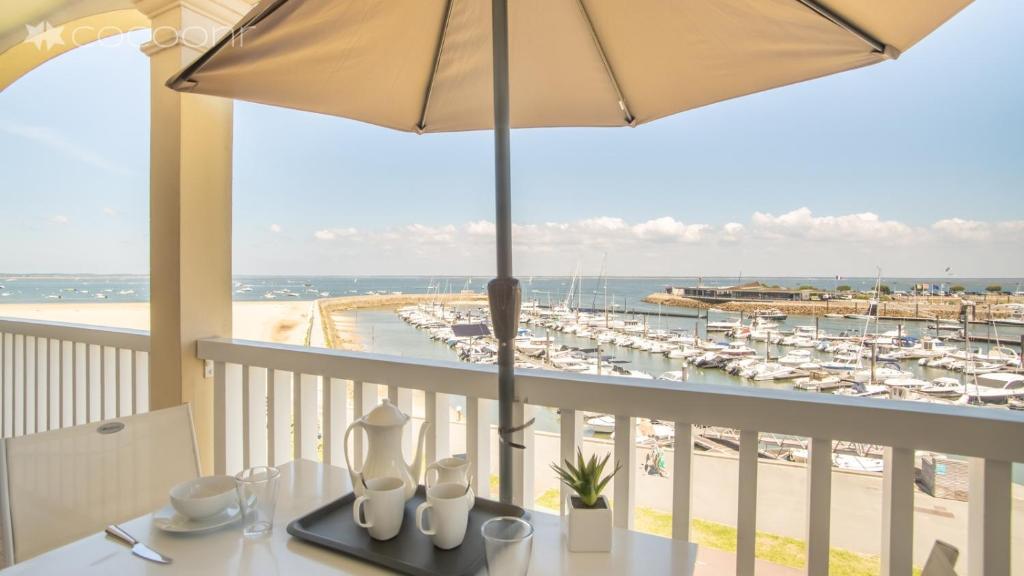 een balkon met een tafel met een parasol en een jachthaven bij Epsom - Appartement en front de mer Arcachon in Arcachon