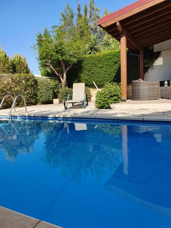 uma piscina com uma cadeira ao lado de uma casa em Melanta Villa em Pissouri