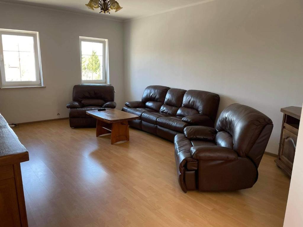 a living room with a leather couch and a table at Apartament Dąbrówno in Dąbrówno