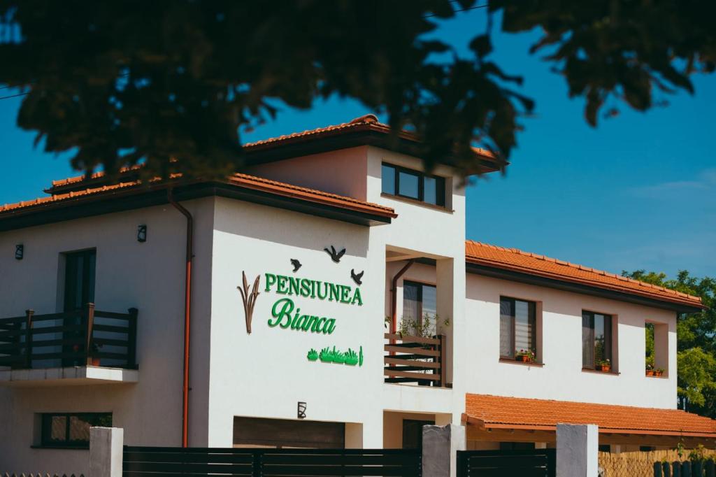 a building with a sign on the side of it at Pensiunea Bianca in Salcioara