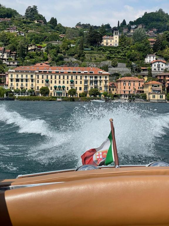 a boat with a flag in a body of water at Grand Hotel Menaggio in Menaggio