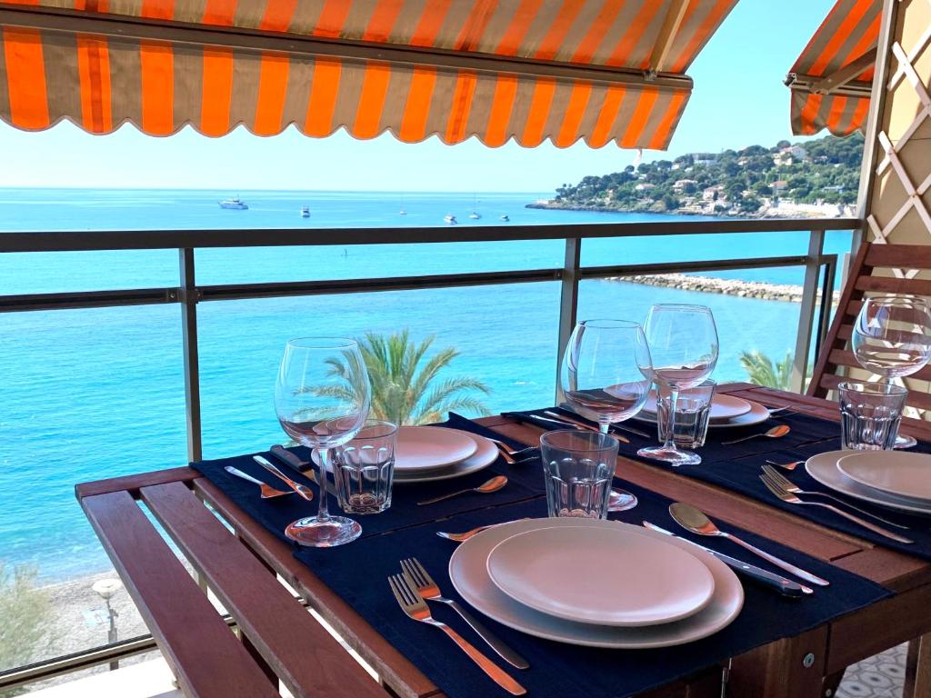 Una mesa con copas de vino y vista al océano. en Appartement Le Schooner, en Roquebrune-Cap-Martin