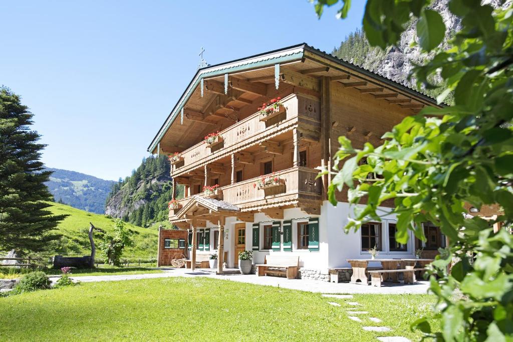 a large wooden building with a green lawn in front of it at Alpenchalet Lacknerbrunn bis 30 P in Mayrhofen