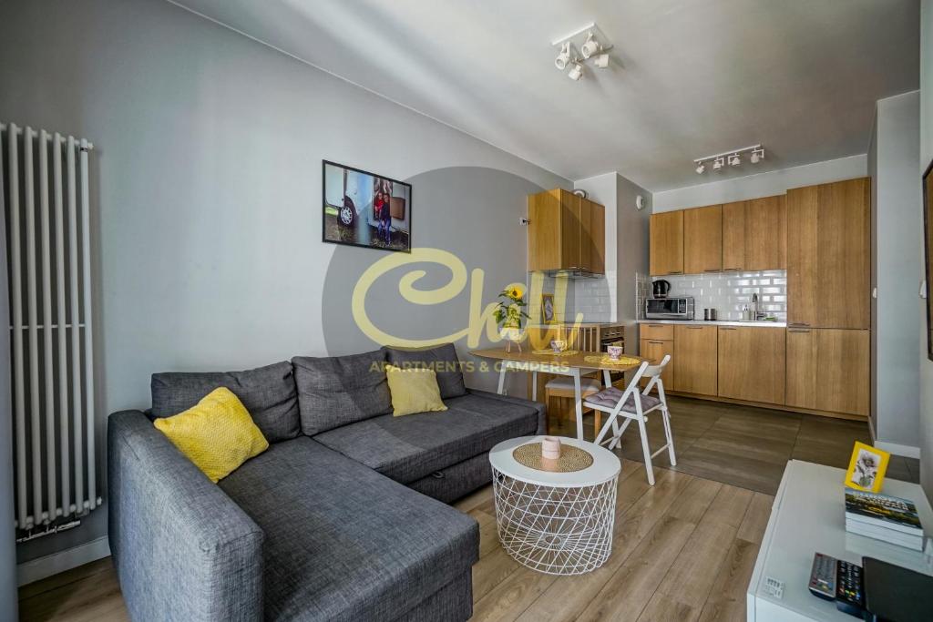 a living room with a gray couch and a table at Chill Apartments City Link in Warsaw
