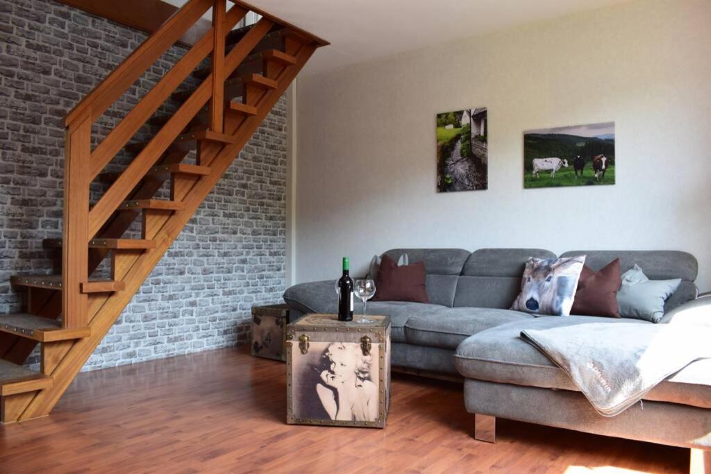 a living room with a couch and a staircase at Ferienwohnung Kölbel Familienurlaub in der Natur in Schmallenberg