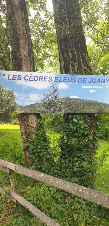 un panneau sur une clôture à côté d'un arbre dans l'établissement Les Cèdres Bleus de Joany, à Viviez