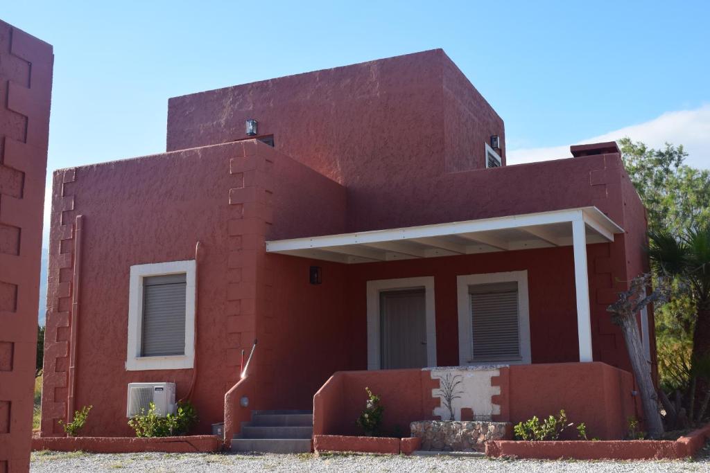 une maison en briques rouges avec des escaliers en face de celle-ci dans l'établissement Pasithea villas, à Frangokastello
