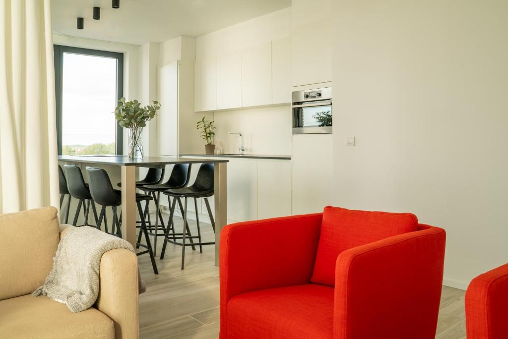 a living room with a red chair and a kitchen at Ostend Port Side incl parking in Ostend