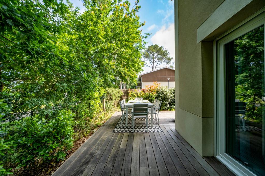 a patio with a table and chairs on a deck at La Carasse in Lège-Cap-Ferret
