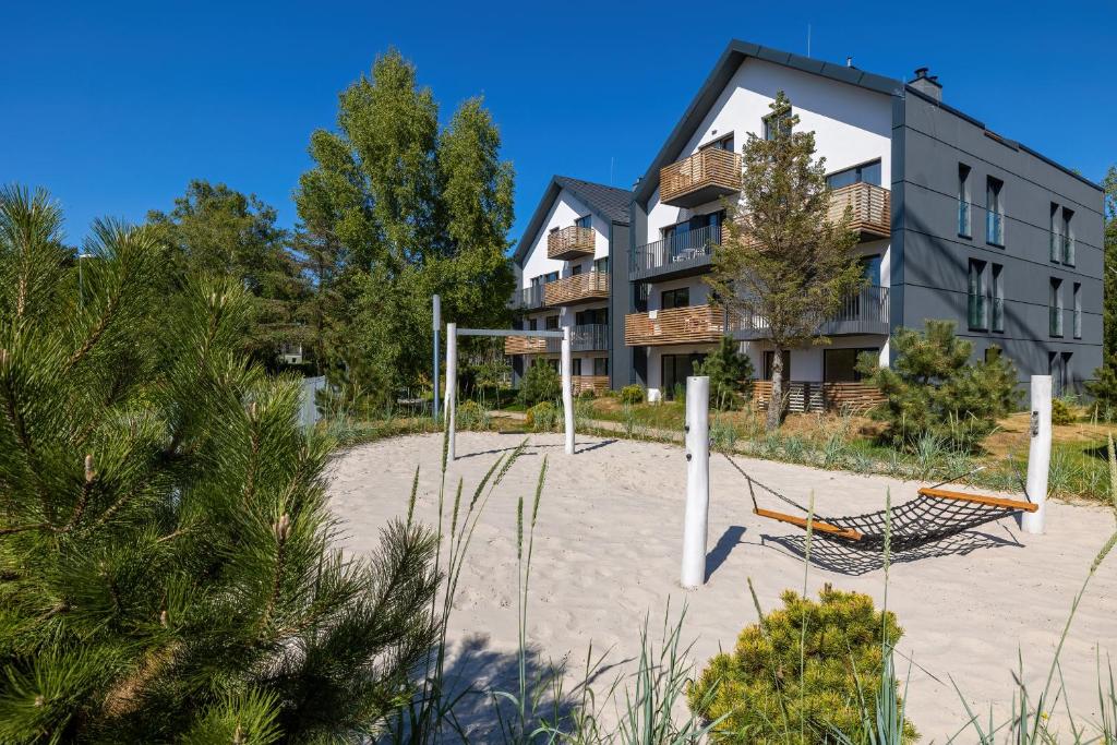a beach with a hammock in front of a building at Apartamenty Południowa 14 by Noclegi Renters in Dźwirzyno