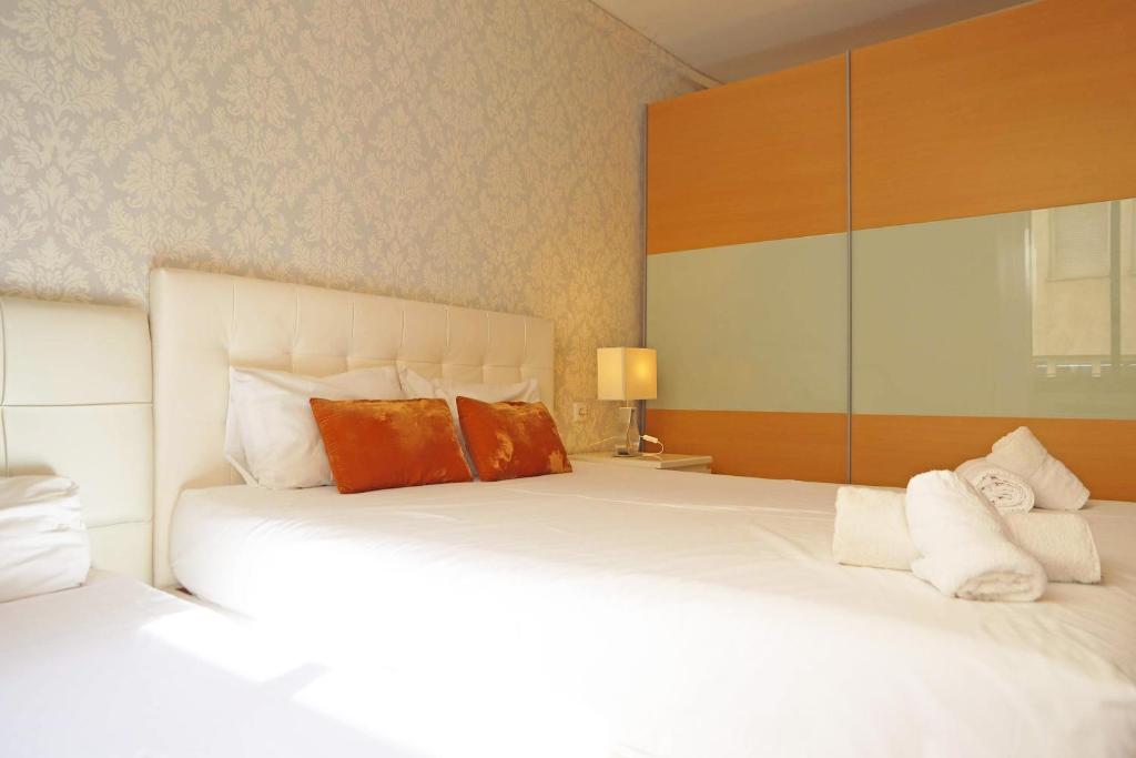 a bedroom with a large white bed with orange pillows at Bcn-rentals apartments in the Old town in Barcelona