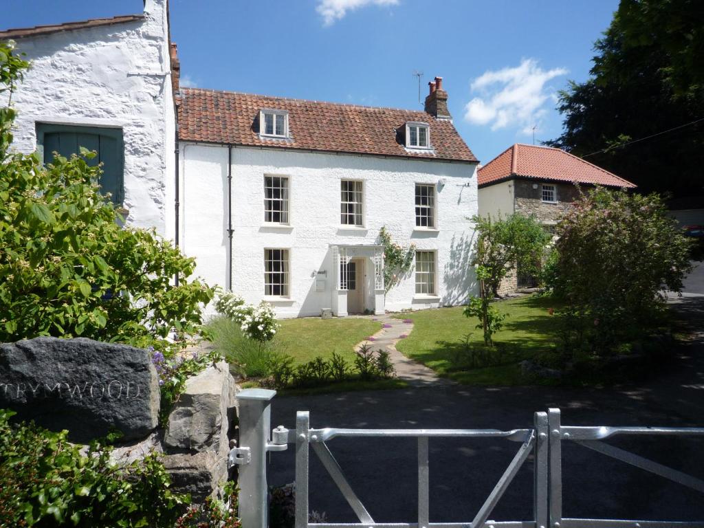 a white house with a fence in front of it at The Old Barn at Trymwood in Bristol