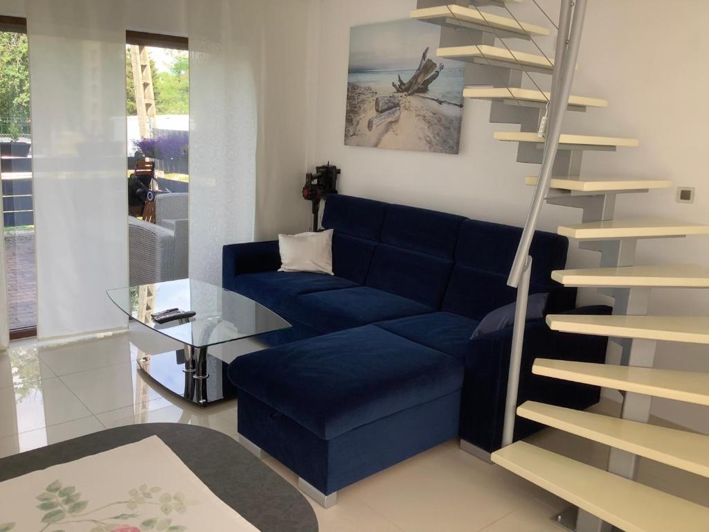 a living room with a blue couch and a spiral staircase at Apartamenty Kris in Mikołajki