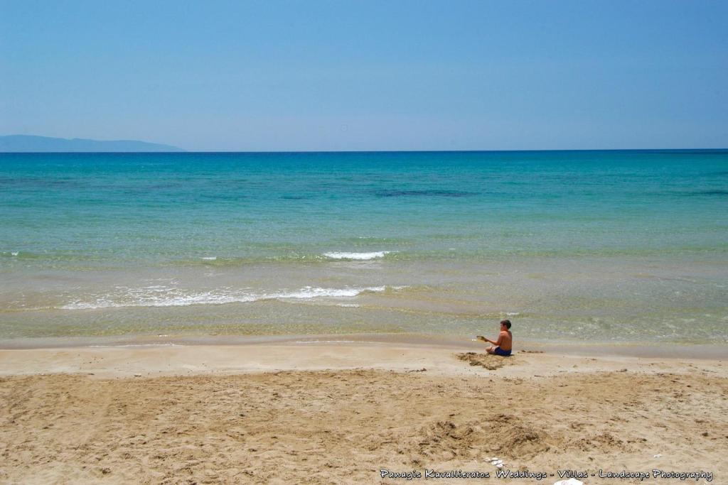 a person sitting on a beach near the ocean at Elisso Apartment in Argostoli