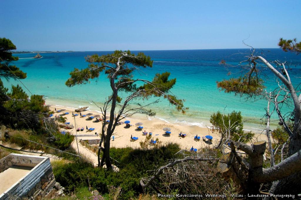 a beach with chairs and umbrellas and the ocean at Elisso Apartment in Argostoli