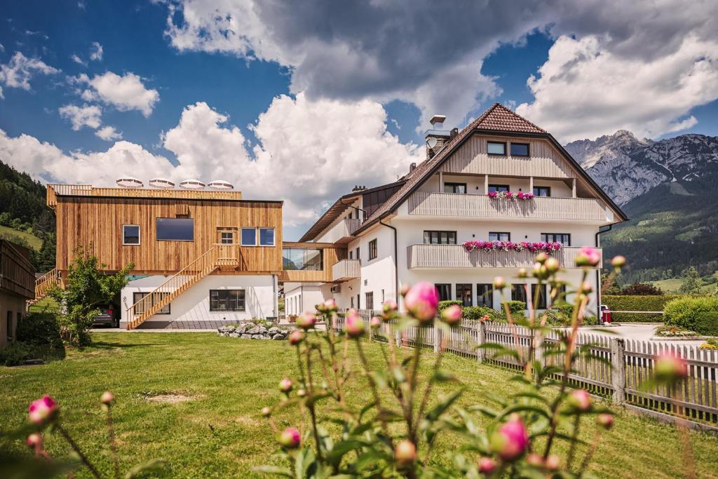 ein Haus auf einem Feld mit Bergen im Hintergrund in der Unterkunft Hotel Loy in Gröbming