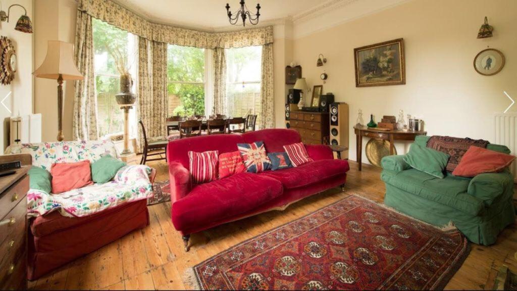 a living room with two couches and a red couch at Lovely 3-Bed House in Cheltenham in Cheltenham