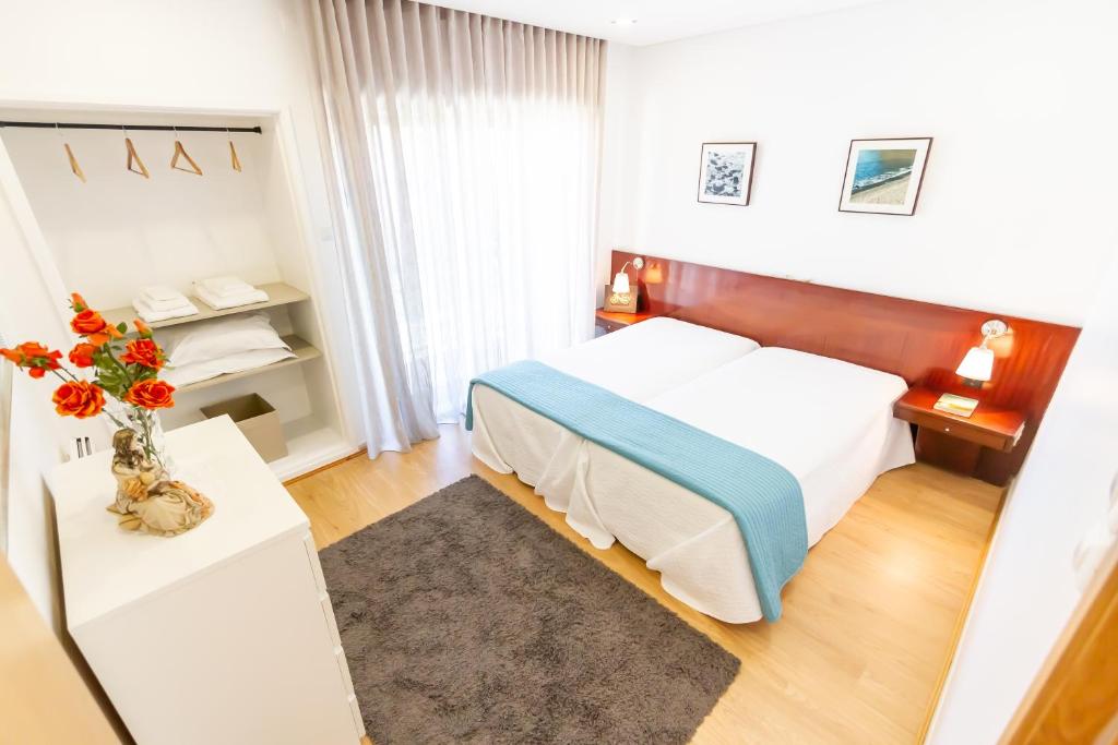 1 dormitorio con 1 cama y un jarrón de flores sobre una mesa en Apartamento Mar & Sol, en Póvoa de Varzim
