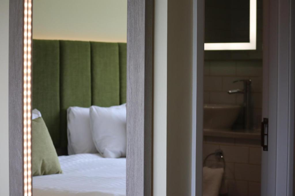 a bedroom with a bed with a green headboard and a tub at Hellidon Lakes Hotel in Daventry
