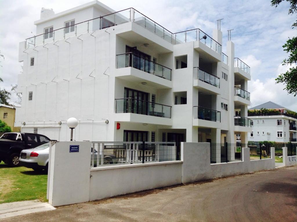 a white building with balconies and a parking lot at Silver Sands in Flic-en-Flac