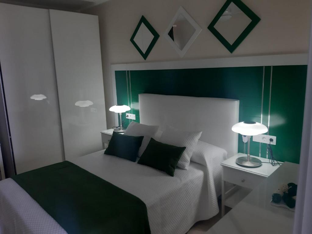 a bedroom with a bed with green walls and two lamps at La Gomera in Gran Tarajal
