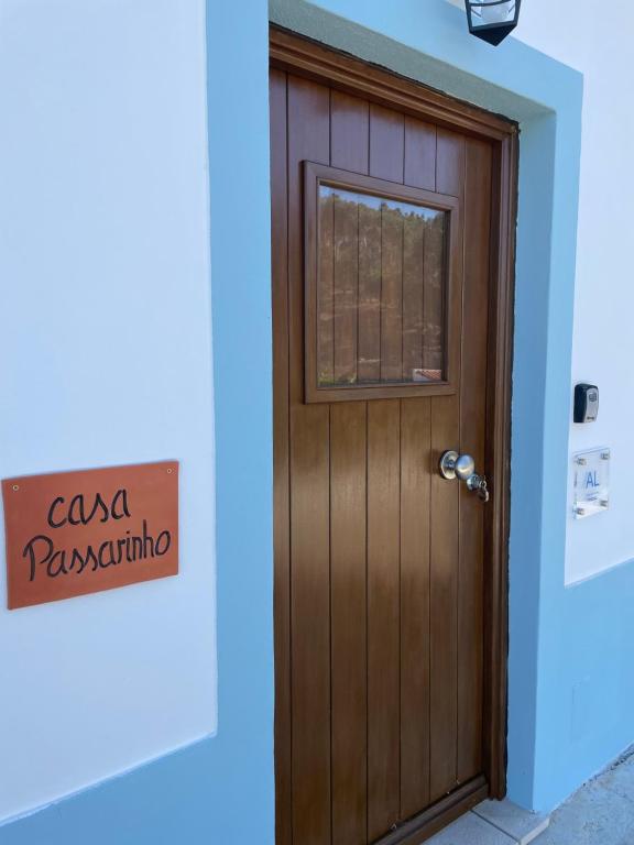 Una puerta de madera en una habitación azul con un cartel. en Casa Passarinho, en Aljezur