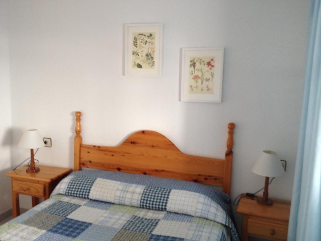 1 dormitorio con 1 cama de madera y 2 lámparas en Apartamentos Torrelaguna, en Vera