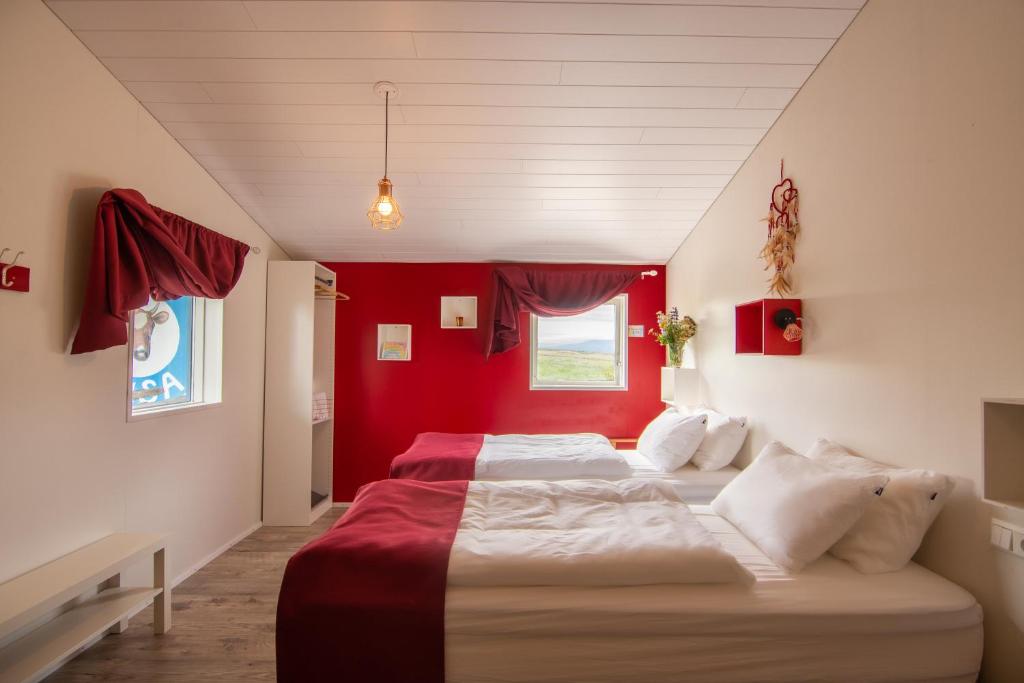twee bedden in een kamer met een rode muur bij Arnarnes Paradise in Arnarnes