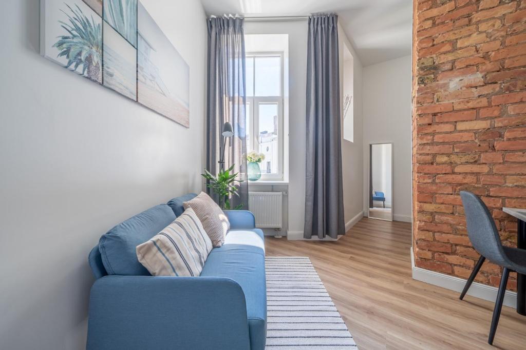a living room with a blue couch and a brick wall at Prestigious Former Library Apartment - Perfect Location in Riga