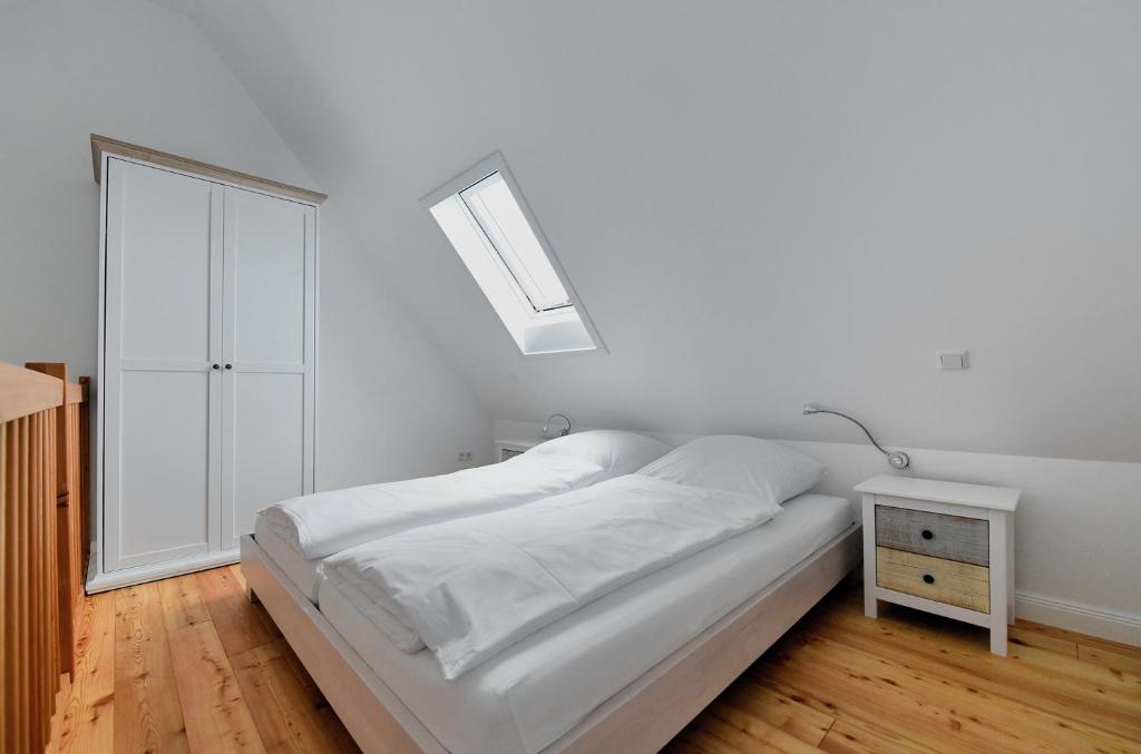 a white bedroom with a bed and a window at Lille Solskin in Tönning