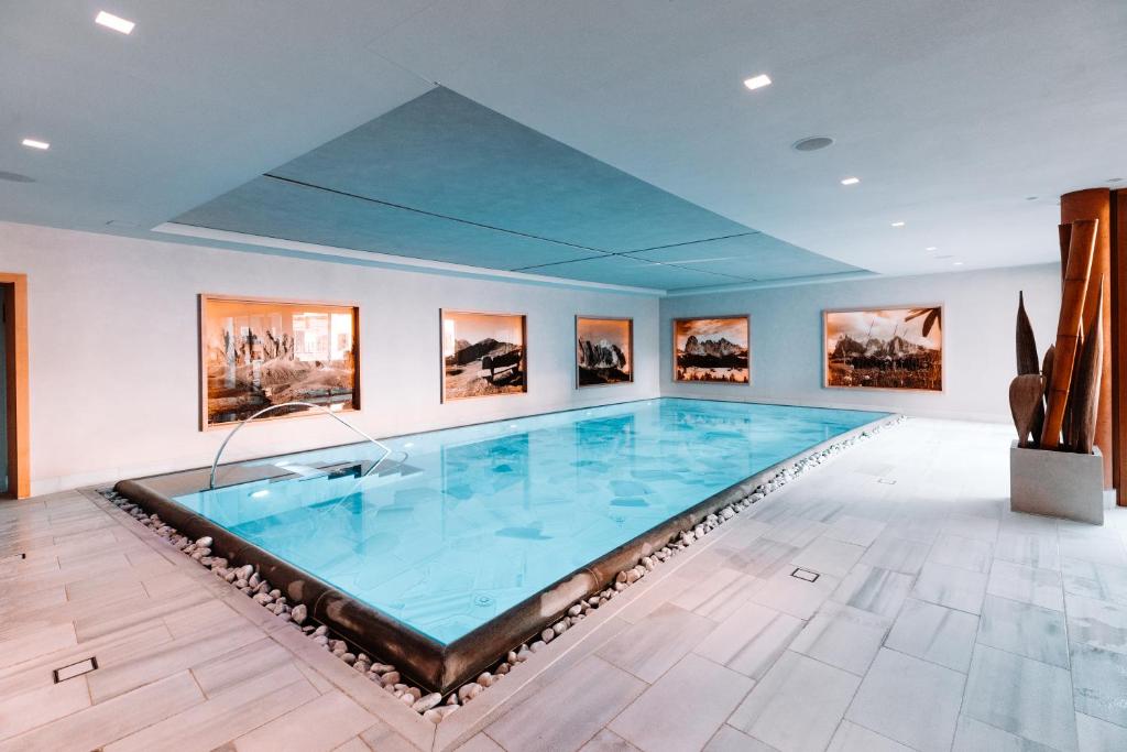 a large swimming pool in a room with paintings at Boutique Hotel Nives - Luxury & Design in the Dolomites in Selva di Val Gardena