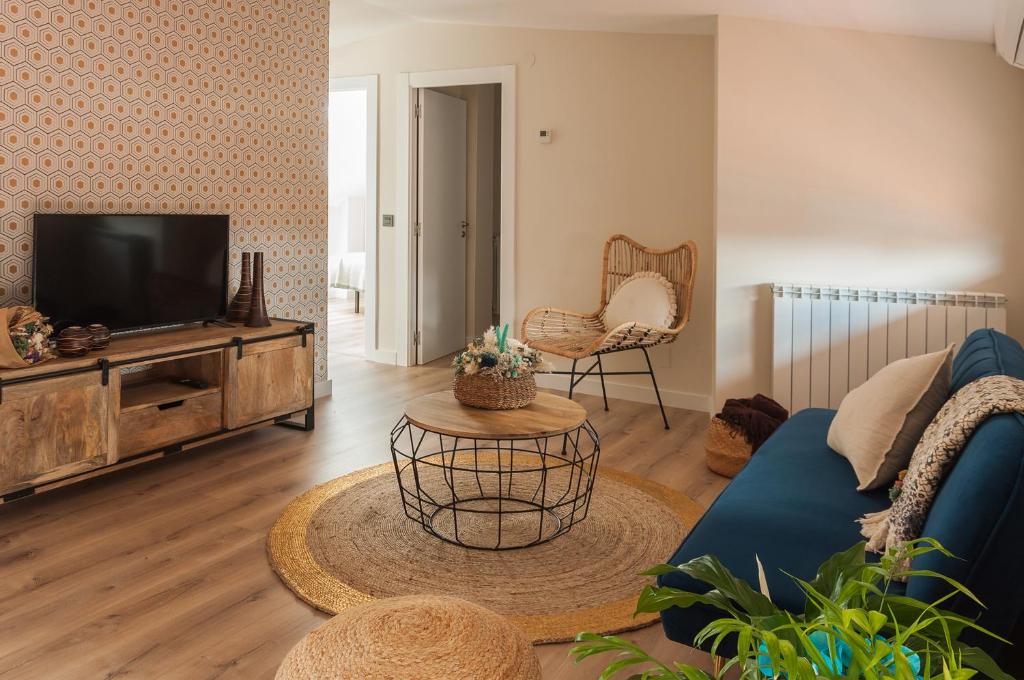 a living room with a tv and a blue couch at Apartamento El Ático in Astorga