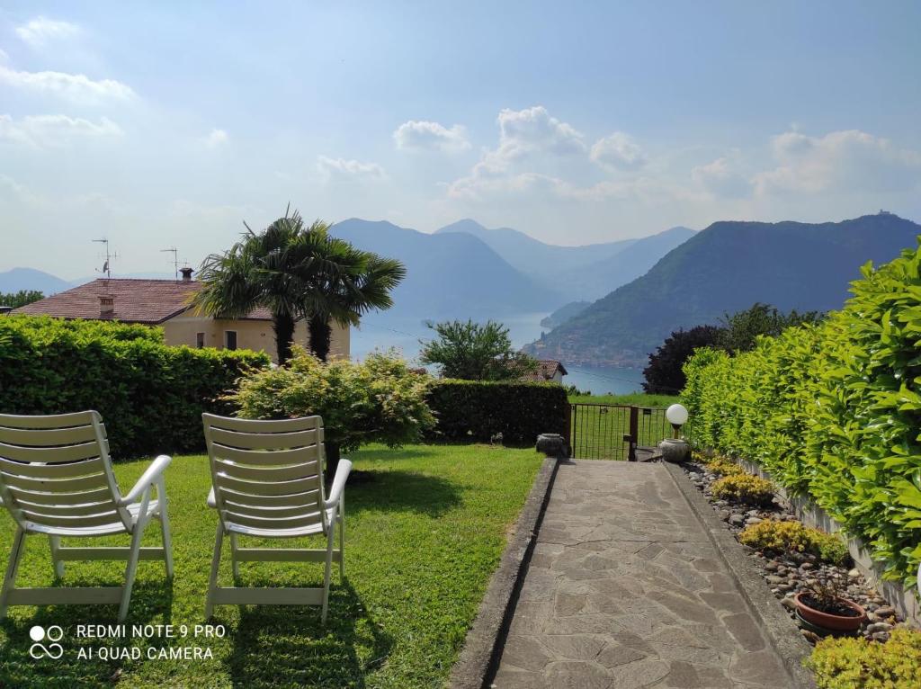 Sulzano Villa con Giardino Vista Lago Parking Free في سولتسانو: كرسيين جالسين على عشب مطل على الجبال