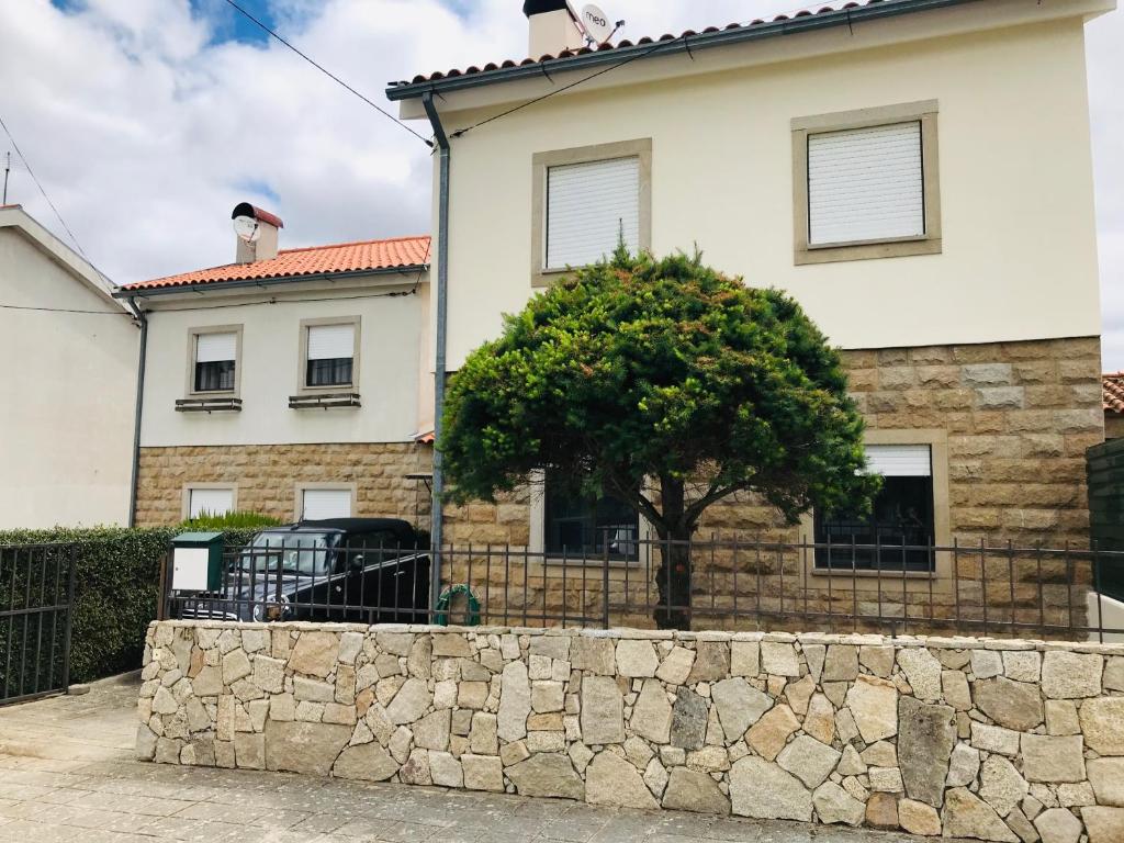 una casa con un árbol delante de una pared de piedra en Casa de Katiolo, en Figueira de Castelo Rodrigo