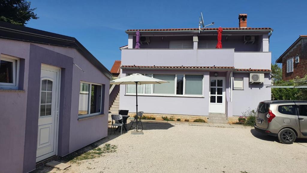 a house with an umbrella and a car parked in the driveway at Apartman Lavanda in Peroj