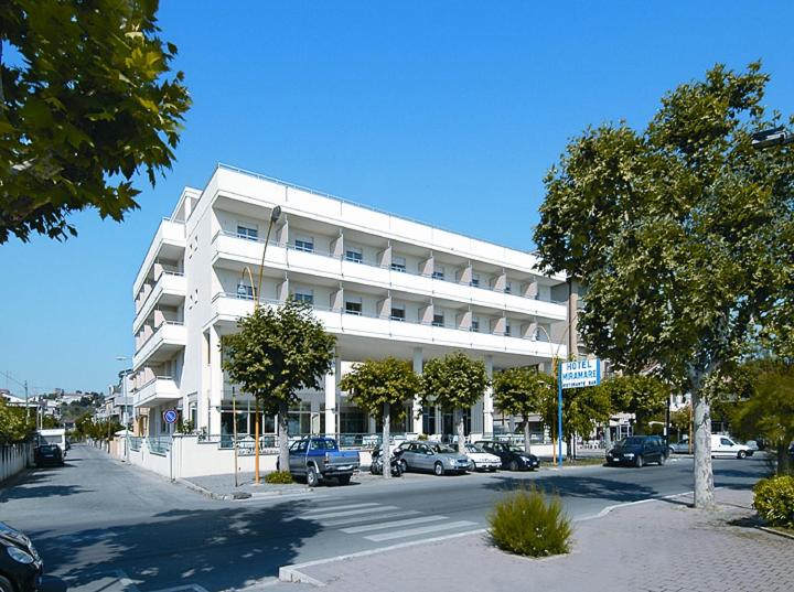 duży biały budynek z samochodami zaparkowanymi przed nim w obiekcie Hotel Miramare w mieście Giulianova