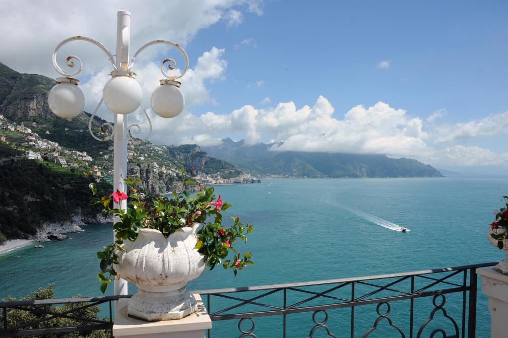 a vase filled with flowers sitting on a balcony overlooking the water at Hotel Belvedere in Conca dei Marini