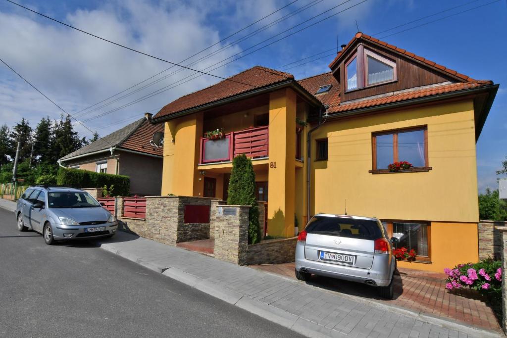 zwei Autos, die vor einem gelben Haus geparkt sind in der Unterkunft VIP Apartmany Besenova in Bešeňová