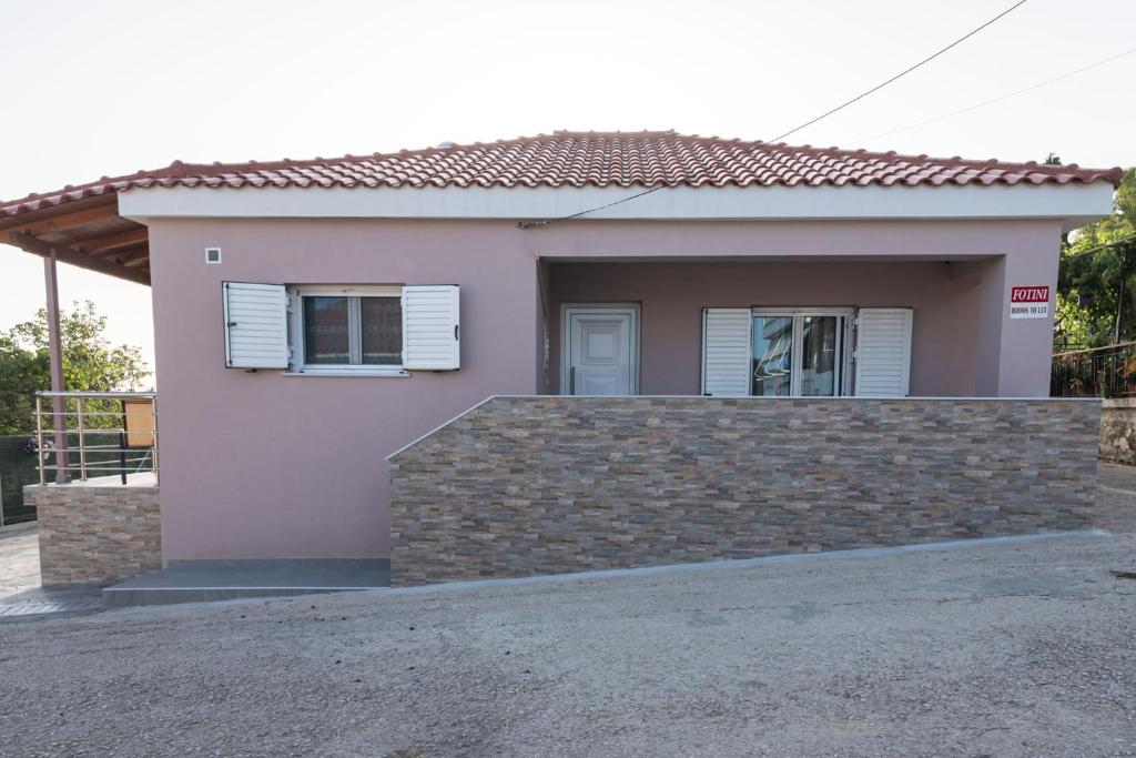 una pequeña casa rosa con una pared de piedra en Fotini Apartments, en Preveza