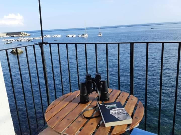 a wooden table with a book on it next to the water at Casa di Sale - Chianalea in Scilla