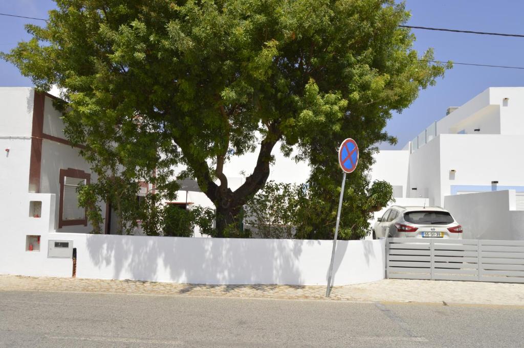 een boom voor een witte muur met een bord bij CASA DA AVÓ in Vila Nova de Cacela