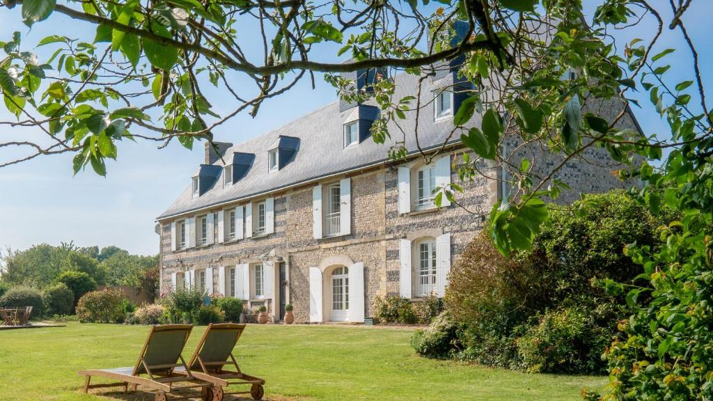 due sedie su un prato di fronte a una casa di Le Manoir des Falaises - Chambres d'hôtes a Saint-Jouin-Bruneval