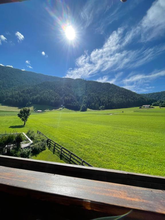 een uitzicht op een groen veld vanuit een treinraam bij Apartments Spirit of Mountains in Rasun di Sopra